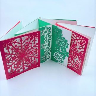 Four laser cut cards with snowflake pattern in red and green.
