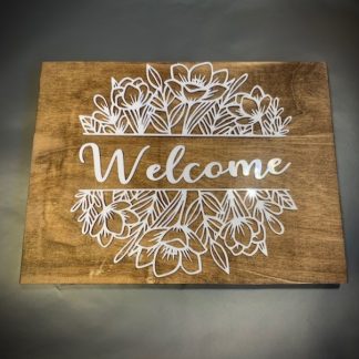 Wooden stained frame with laser cut lettering from white acrylic that says 'welcome'