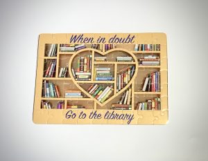 Cardboard puzzle with sublation image on it. "When in doubt go to the library" with books on a shelfs 