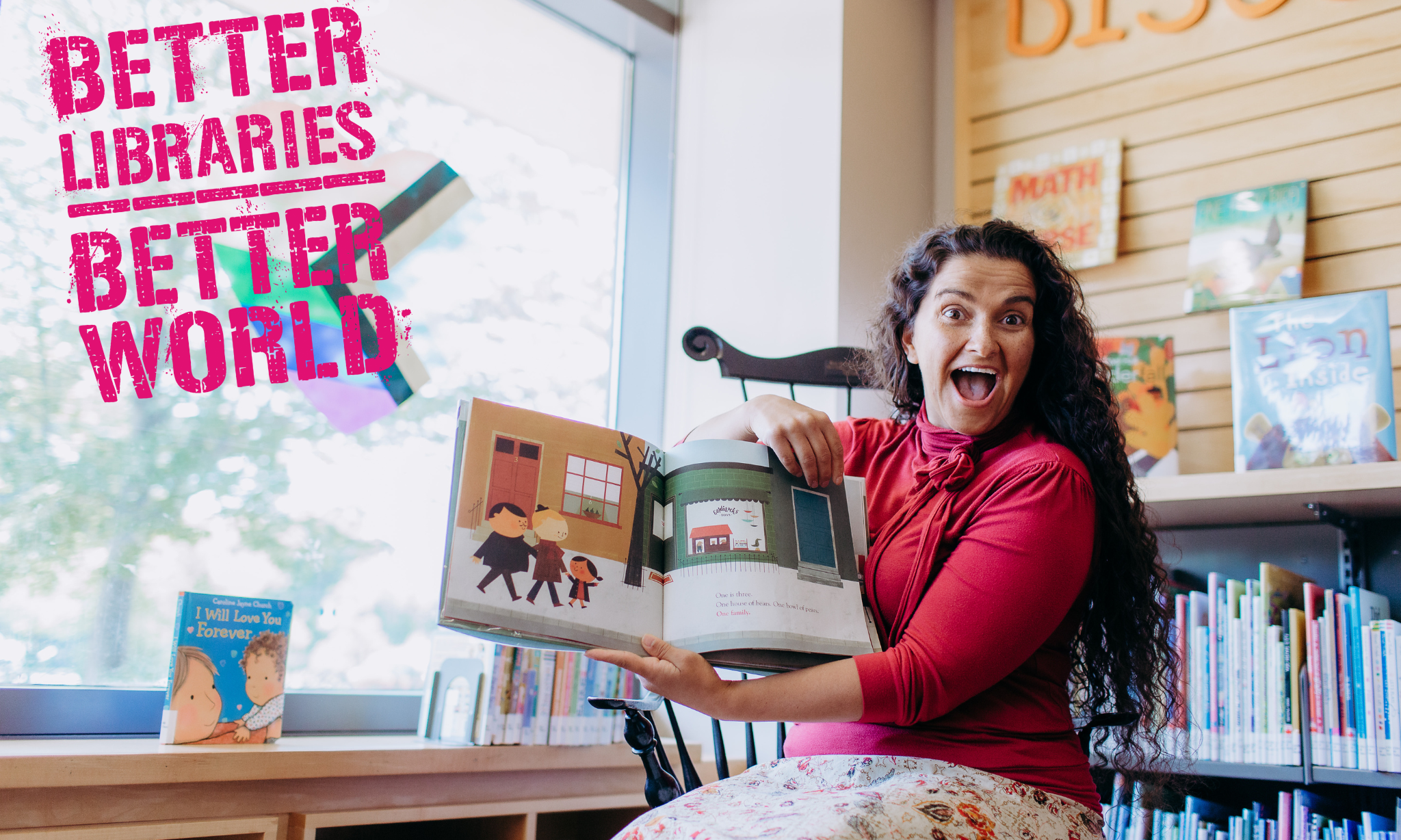 woman smiling in library holding children's book