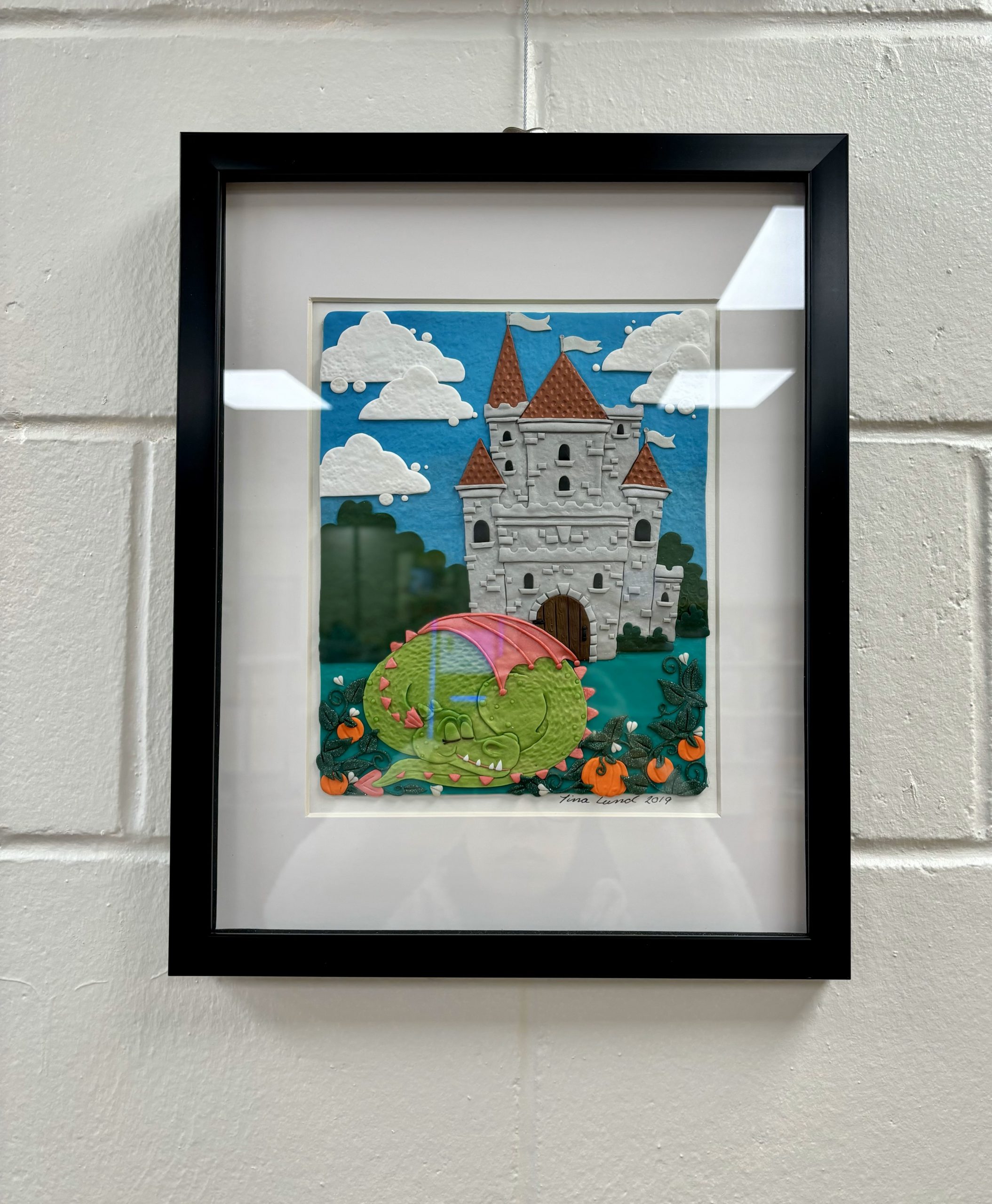 polymer clay art of a sleeping dragon in front of a castle