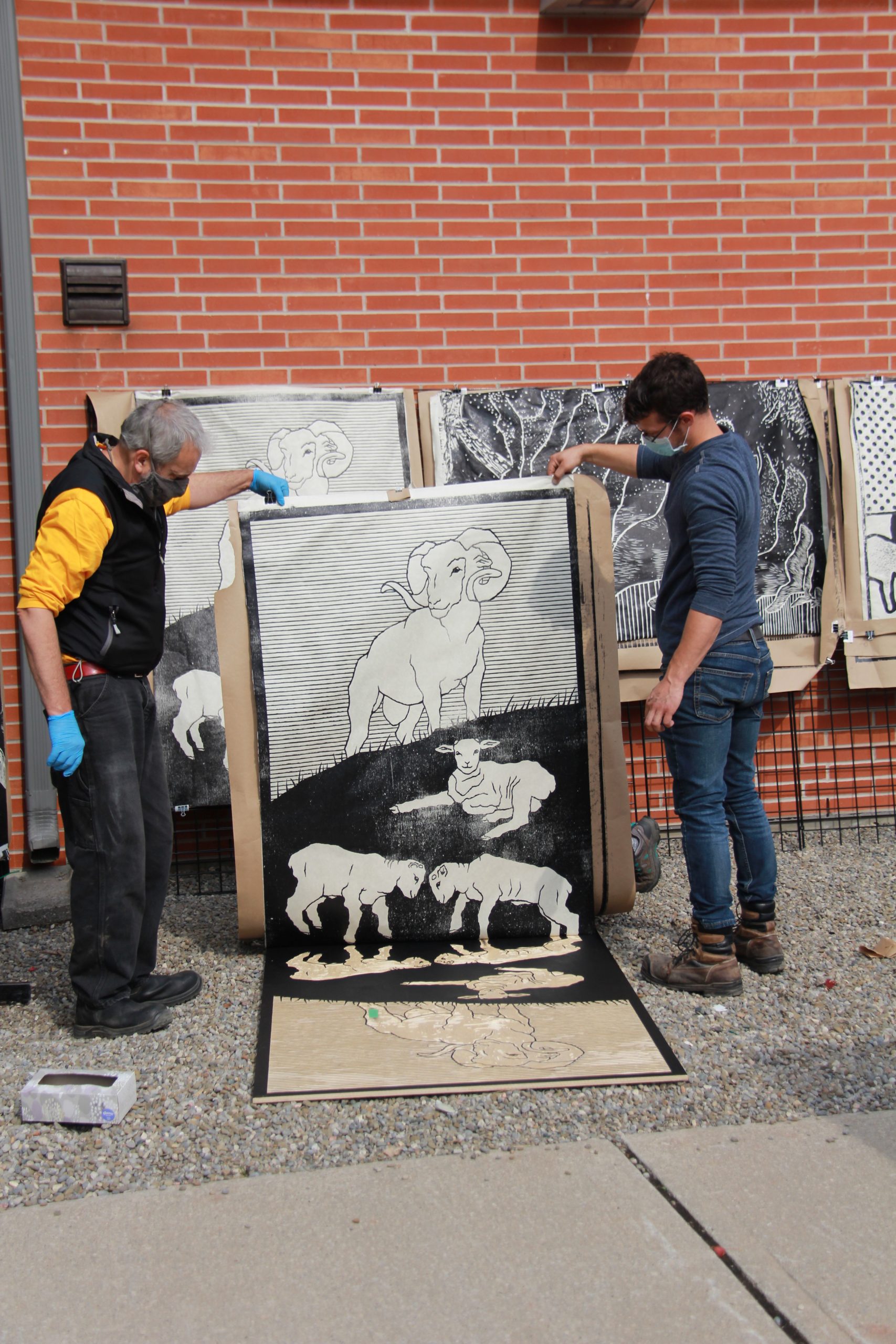 two men lifting up a large print of big horn sheep